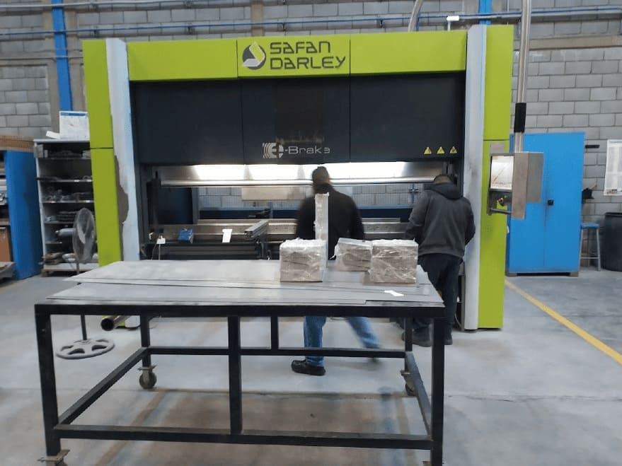 Operarios trabajando en una prensa dobladora de lámina marca Safan Darley.