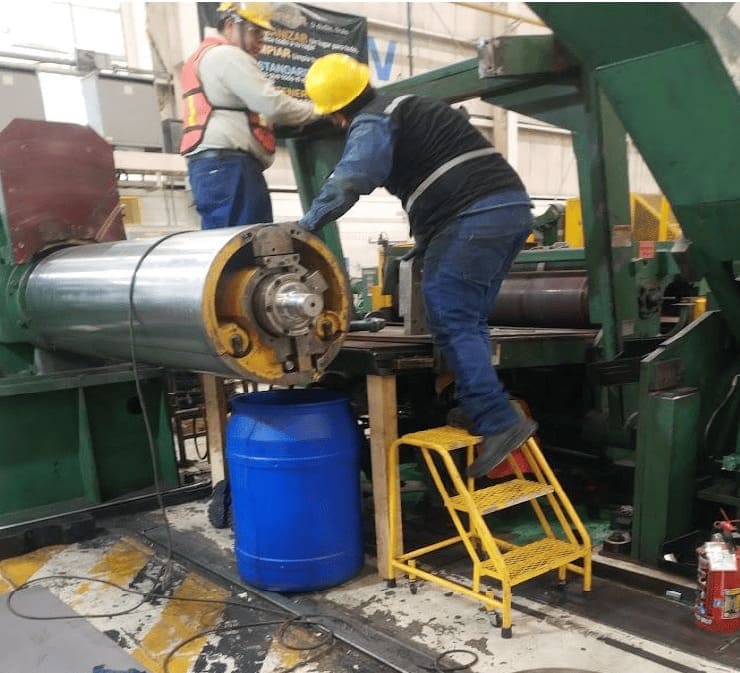Técnico realizando reparación mecánica en un rodillo industrial pesado.