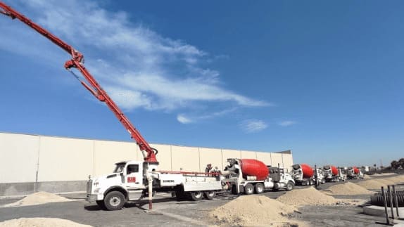 Flotilla de camiones de concreto realizando vaciado para obra civil industrial.