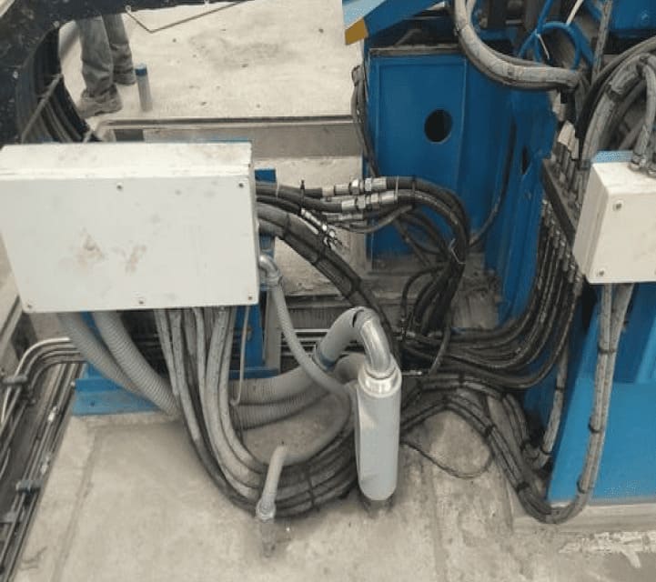 Cableado y tuberías de un sistema neumático y eléctrico en la base de una máquina.